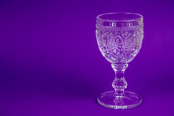 one empty glass on purple background  and plece for text from left side