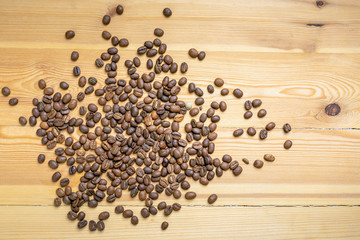 Roasted coffee beans randomly dumped on a wooden table