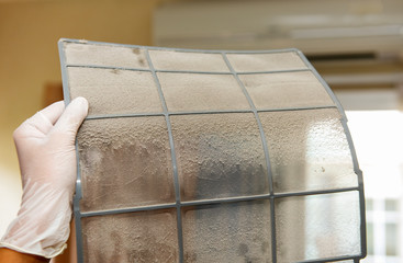 Hand with white gloves pointing thick dust on the air conditioning filters