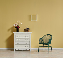 Yellow wall background in the room, white cabinet, chair and frame decor.
