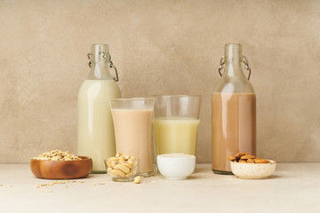 Dairy alternative. Rice, oat, cashew and chocolate almond milk in bottles and glasses on beige background. Healthy protein vegan drink.