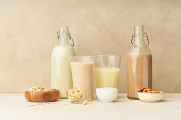 Dairy alternative. Rice, oat, cashew and chocolate almond milk in bottles and glasses on beige background. Healthy protein vegan drink.
