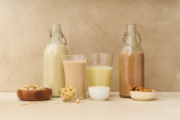 Dairy alternative. Rice, oat, cashew and chocolate almond milk in bottles and glasses on beige background. Healthy protein vegan drink.