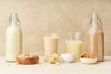 Dairy alternative. Rice, oat, cashew and chocolate almond milk in bottles and glasses on beige background. Healthy protein vegan drink.