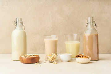 Dairy alternative. Rice, oat, cashew and chocolate almond milk in bottles and glasses on beige background. Healthy protein vegan drink.