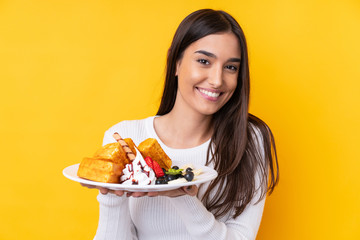 Young brunette woman holding waffles over isolated background