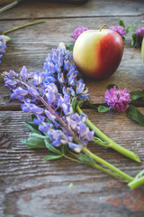 bunch of lilac flowers on wooden table and apple