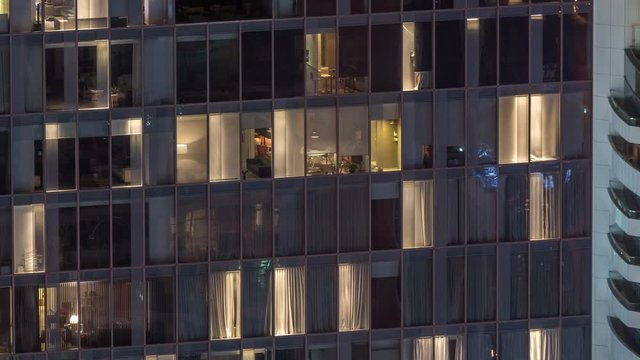 Night view of office and apartment building timelapse. High rise skyscraper with blinking windows with people moving inside. Aerial view from above