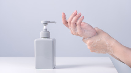 Washing hands. Asian young woman using liquid soap to wash hands, concept of hygiene to protective pandemic coronavirus isolated on gray white background, close up.