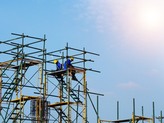 Construction workers working on scaffolding, Man Working on the Working at height with blue sky at construction site