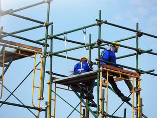 Construction workers working on scaffolding, Man Working on the Working at height with blue sky at construction site