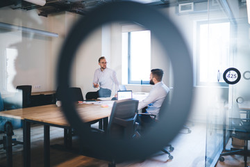 Caucasian male colleagues in smart casual clothing discussing strategy for business project analyzing information while brainstorming in office workspace, intelligent analysts collaborating indoors