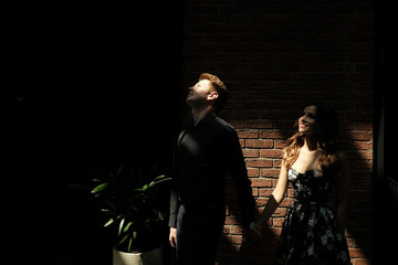 beautiful couple-a girl in a magnificent dress and a guy in a black shirt and trousers are in a building with a beautiful interior