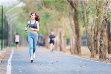 Fototapeta premium Asia woman running in park and listening to music with headphones.