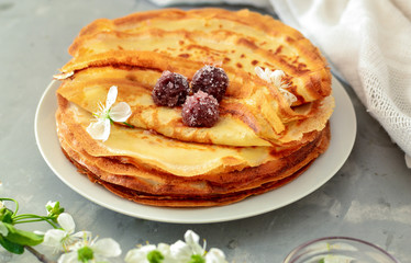 Thin homemade pancakes. Light background. Beautiful and delicious breakfast at home or in the cafe. Thin aromatic pancakes with cherries and berries. Side view. Light napkin.
