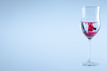 Wine glass whit red liquid drops. Glass isolated.