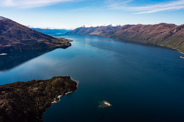 Naklejka na ściany i meble Stunning aerial image of the Wanaka lake with the snowy Mount Aspiring in the background on a sunny winter day, New Zealand