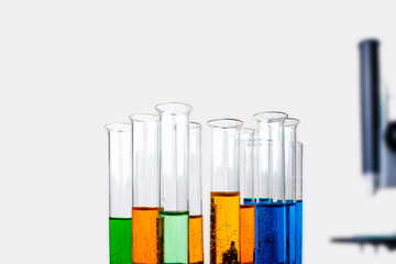 Laboratory test tubes with liquid and blurred metal microscope isolated on light background