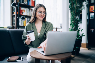 Happy female typing on laptop in library