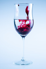 Powerful color splash in wine glass. Red ink, glass isolated.