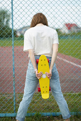 Redhead white girl with skateboard near fence