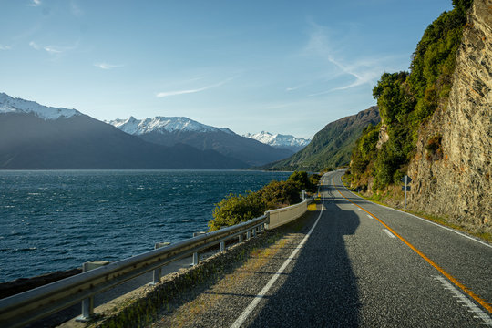 Beautiful sunset image of the Haast Pass road with Wanaka Lake on the left and snow capped mountains in the background on a winter day, New Zealand