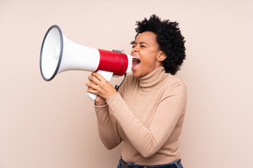 African american woman over isolated background shouting through a megaphone