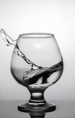 On a white background with a glass of water. Liquid spilled from the glass