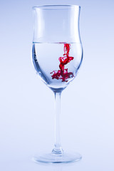 Powerful color splash in wine glass. Red ink, glass isolated.