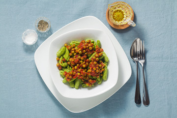 Italian fresh traditional sardinian pasta gnocchi with spinach and green pea tomato sauce. spring pasta for easter holidays.