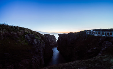 Fototapeta premium Beautiful panorama of an orange sunset at Pancake Rocks on a sunny winter day in Punakaiki, New Zealand