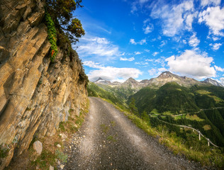 dirt road in Switzerland, green meadows and mountains