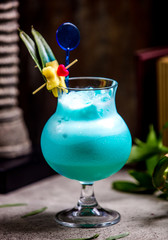 blue cocktail with leaves and fruits on top