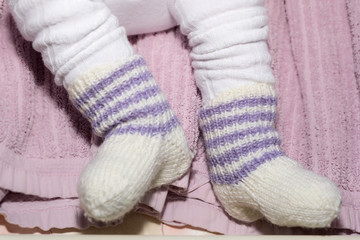 Fototapeta na wymiar Child's Feet in Hand Knitted White Wool Socks.