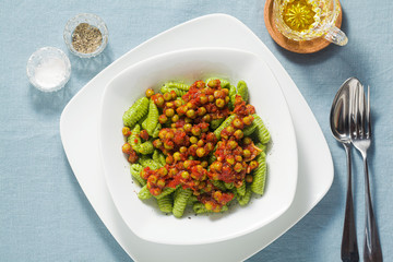 Italian fresh traditional sardinian pasta gnocchi with spinach and green pea tomato sauce. spring pasta for easter holidays.