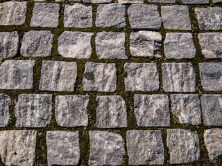 Cobbled stone road in Bucharest. Old cobbled street with moss between stones