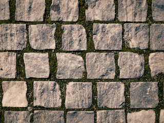 Cobbled stone road in Bucharest. Old cobbled street with moss between stones