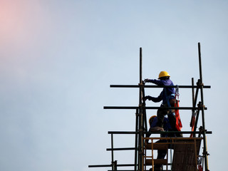 Construction workers working on scaffolding, Man Working on the Working at height with blue sky at construction site