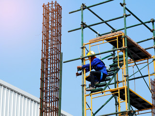 Construction workers working on scaffolding, Man Working on the Working at height with blue sky at construction site