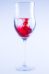 Powerful color splash in wine glass. Red ink, glass isolated.