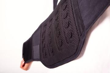 Electric massager. For the lower back with a demonstration on the lower back of the model. Part of the body of the model is isolated on a white background.