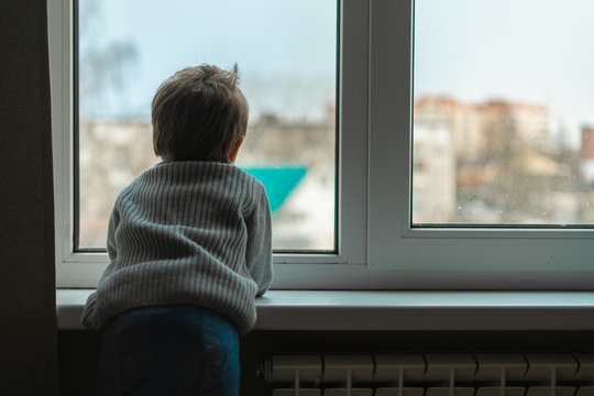 Little boy looks out the window and wants to go outside