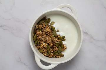 granola with seeds and yogurt in a white cup
