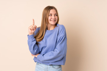 Teenager Ukrainian girl isolated on beige background pointing up a great idea