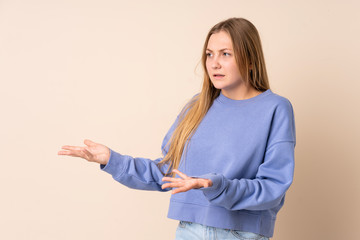 Teenager Ukrainian girl isolated on beige background with surprise expression while looking side