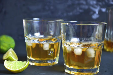 Drink cold tea with ice cubes and mint in two glass goblets a dark black background. Alcoholic or non-alcoholic mahito. whiskey or scotch tape, with lime or lemon