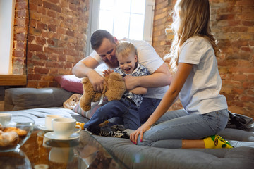 Mother, father and son at home having fun, comfort and cozy concept. Looks happy, cheerful and joyful. Beautiful caucasian family. Spending time together, playing, watching cinema, lying on sofa.