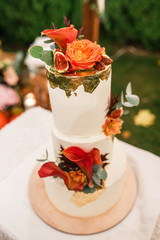 wedding cake stands on a served table and is decorated with flowers