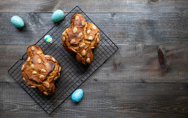 Colomba Pasquale, a typical Italian Easter cake with color eggs on the wooden table. Fresh baked, top view.
