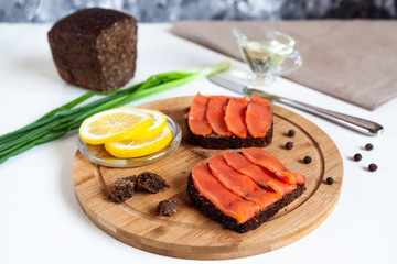 Slice of pink salmon fish on a slice of bread and fresh lemon on the wooden plate